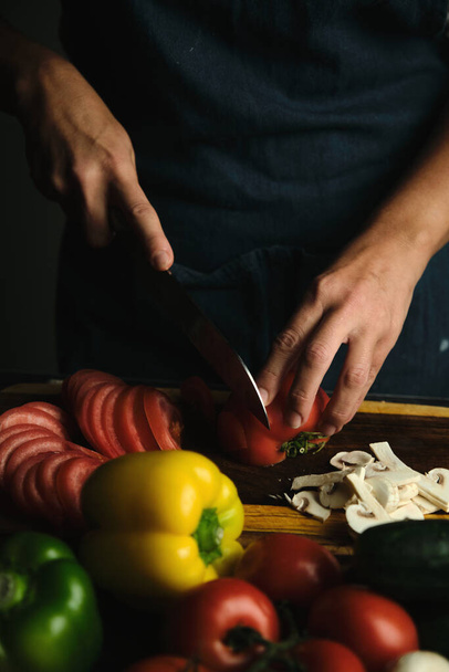 zbliżenie kucharzy ręce krojenie pomidorów, warzywa leżą wokół - Zdjęcie, obraz