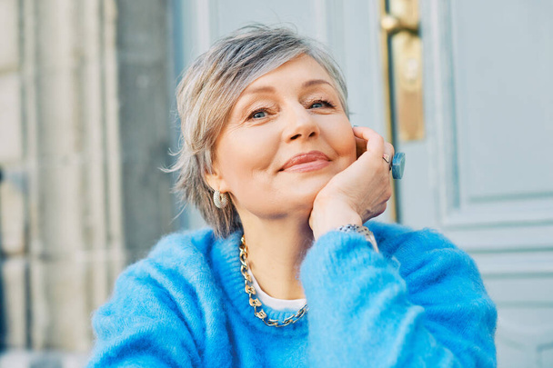 Retrato al aire libre de una hermosa mujer de 55 a 60 años, con jersey azul - Foto, imagen