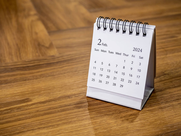 Luty 2024 na biurku kalendarza dla organizatora zaplanować i przypomnieć na tle drewna z przestrzeni, minimalny styl. Biały mały kalendarz stołowy ze stroną drugiego miesiąca, Szczęśliwego Nowego Roku 2024. - Zdjęcie, obraz