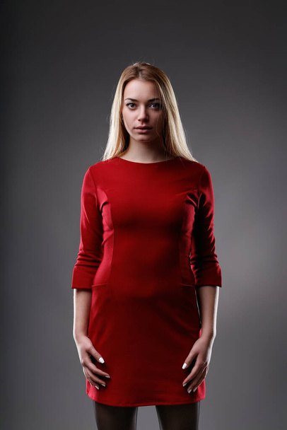 Το αταλάντευτο βλέμμα συναντά την κάμερα, με την παρουσία της στο κόκκινο φόρεμα ολοφάνερη αλλά συγκρατημένη - Φωτογραφία, εικόνα