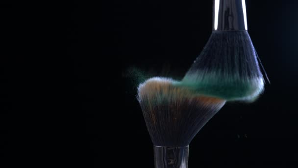 Kosmetikaccessoires, die sich gegenseitig in Super-Zeitlupe in orangen und grünen Farben vor schwarzem Hintergrund bürsten, aufgenommen mit einer Hochgeschwindigkeitskamera bei 1000 fps - Filmmaterial, Video