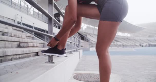 Schoenen, knoop en handen van een vrouw buiten in het stadion voor training, oefening en training. Sport, voeten en fitness op trappen en trappen met pauze met sneakers en voet in een fitnessclub voor wellness. - Video