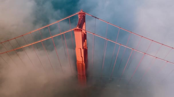 Eeppinen liike tausta maaginen sumu pilvi ympärillä punainen torni Golden Gate silta San Franciscossa, USA 4K. Henkeäsalpaava antenni Golden Gate Bridge keventää kultainen auringonpaiste auringonlaskun tai auringonnousun. - Materiaali, video