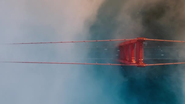赤いゴールデンゲートブリッジの周りを漂う劇的なティールオレンジ色の雲の確立. ゴールデンゲートブリッジの道路で運転する車の垂直オーバーヘッド航空機. サンフランシスコのランドマークのBロールビデオ - 映像、動画