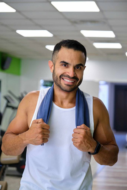 Портрет сильного іспаномовного чоловіка в спортзалі, який посміхається і дивиться на камеру. - Фото, зображення
