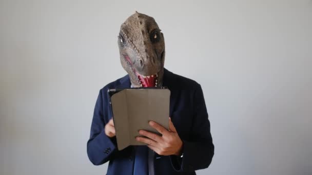 üzletember dinoszaurusz maszk tartja tabletta pc beltéri - Felvétel, videó