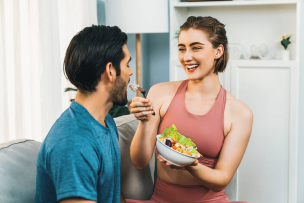 Gesundes sportliches und vegetarisches Paar in Sportbekleidung mit einer Schüssel Obst und Gemüse. Gesunde Küchennahrung und veganer Lebensstil für Fitness-Körperbau bei Frohsinn-Home-Konzept. - Foto, Bild