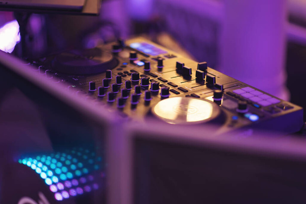 DJ kontroler na imprezie - życie nocne ludzie koncepcja stylu życia. DJ wymieszać stół z niebieskimi tonami w imprezie klubu nocnego. DJ sound control konsola do mieszania muzyki tanecznej i laptopa w klubie disco. - Zdjęcie, obraz