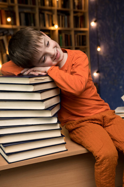 уставший маленький мальчик спит на стопке книг - Фото, изображение