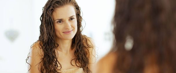 young woman with wet hair looking in mirror - Photo, Image