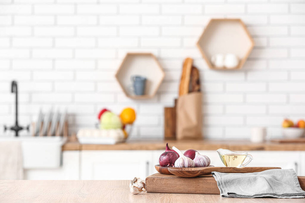 Дерев'яна дошка, свіжі овочі та морський човен з оливковою олією на столі на кухні - Фото, зображення