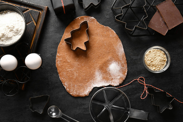 Cortadores, massa fresca e ingredientes para biscoitos de gengibre em fundo preto - Foto, Imagem