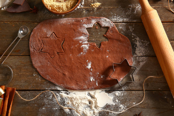 Cortadores, massa fresca e ingredientes para biscoitos de gengibre em fundo de madeira marrom - Foto, Imagem
