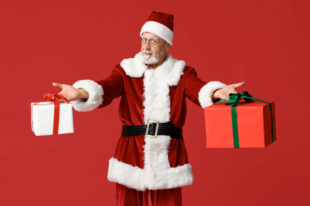 Cool Santa Claus con cajas de regalo sobre fondo rojo - Foto, Imagen