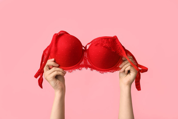 Female hands with sexy bra on pink background, closeup - Photo, Image