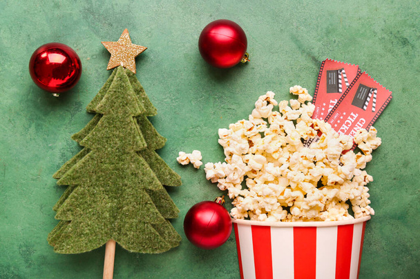 Bucket of popcorn with cinema tickets and Christmas decor on green grunge background - Photo, Image