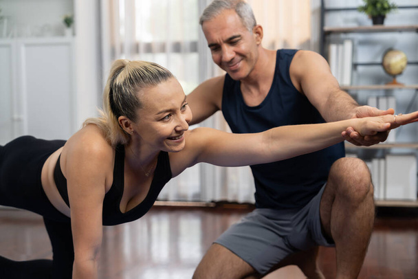 Szczęśliwa aktywna para seniorów w odzieży sportowej jest pomocna i pomaga w postawie jogi razem w domu. Zdrowy starszy mężczyzna i kobieta styl życia z ćwiczeniami jogi. Skutki - Zdjęcie, obraz