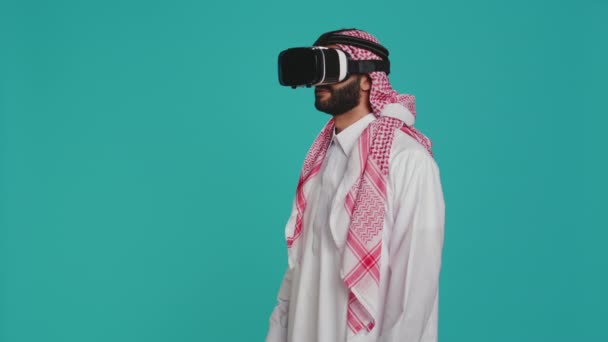 Парень с Ближнего Востока, использующий очки vr в студии, наслаждается съемкой с симуляцией виртуальной реальности на интерактивной гарнитуре. Молодой взрослый веселится с 3D инновации, современное хобби и устройства. - Кадры, видео