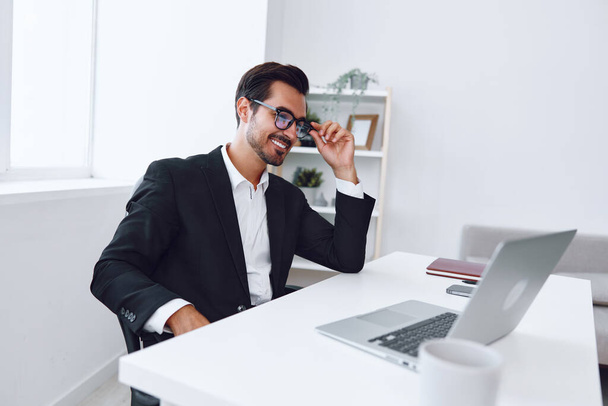 Человек в офисе бизнесмен сидит за столом и работает в ноутбуке, финансы и стартап концепции, работая образ жизни в ярком офисе. Высокое качество фото - Фото, изображение