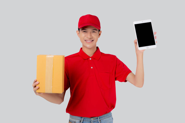 Portret van een jonge aziatische man in uniform staande doos of pakket en digitale tablet tonen en presenteren geïsoleerde witte achtergrond, levering man express en scheepvaart, logistiek en lading. - Foto, afbeelding