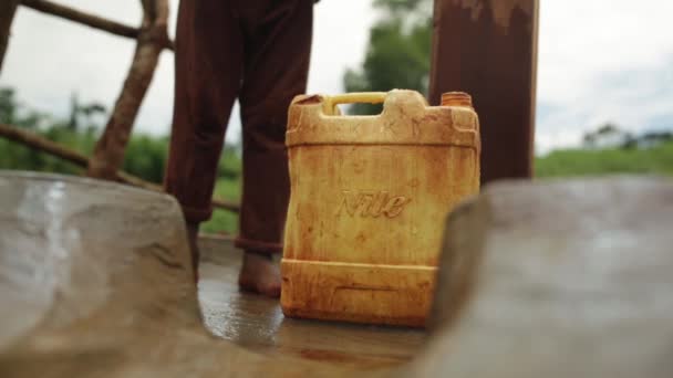 Uma criança africana jovem pegando e saindo com um recipiente de água de plástico depois de enchê-lo
 - Filmagem, Vídeo