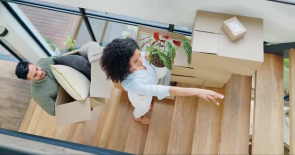 Couple, new home and boxes for moving, planning interior design and talking of ideas on stairs, property or real estate. Happy interracial people with cardboard, plants and vision for house above. - Footage, Video