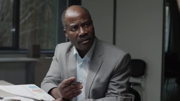 Über-Schulter-Handschuss unzufriedener afroamerikanischer Manager bei Verhandlungen mit nicht identifizierten Mitarbeitern während einer Projektdiskussion in einem Büro-Meeting - Filmmaterial, Video