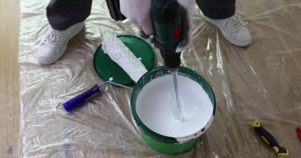Maître réparateur mélangeant la peinture blanche dans le seau à l'aide d'une perceuse avec mélangeur gros plan film 4k au ralenti. Travaux de finition pour la réparation d'appartements et de maisons concept - Séquence, vidéo