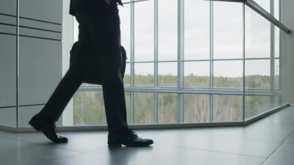 Laag deel schot van onherkenbare zakenman lopen in kantoor atrium wachten op zakenpartner - Video