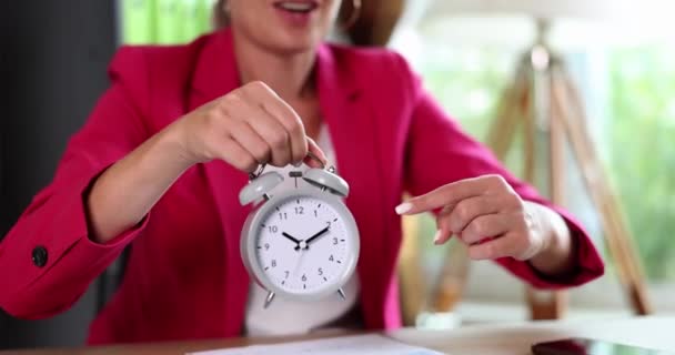 Businesswoman in pink suit pointing with index finger at alarm clock at workplace closeup 4k movie slow motion. Time management concept - Footage, Video