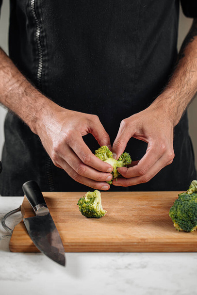 Chef separating broccoli on a wooden board preparing healthy meal - Photo, Image