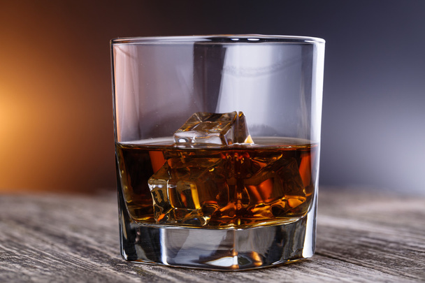 Bicchiere di whisky e ghiaccio su un tavolo di legno
. - Foto, immagini