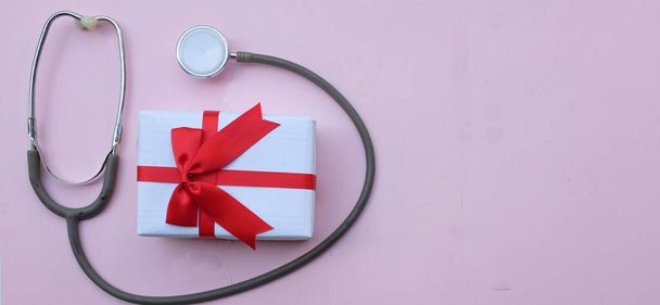 stéthoscope médical avec coffret cadeau isolé sur fond pastel rose. concept noël et nouvelle année.photo horizontale - Photo, image