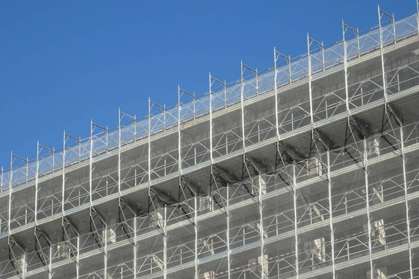 ανακαίνιση της εξωτερικής όψης κτιρίου, μεταλλικές σκαλωσιές με δίχτυ προστασίας - Φωτογραφία, εικόνα