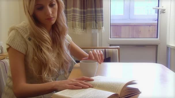 kobieta pijąca kawę i czytająca książkę - Materiał filmowy, wideo