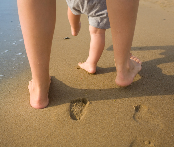 Mère et enfant marchant sur une plage de sable
 - Photo, image