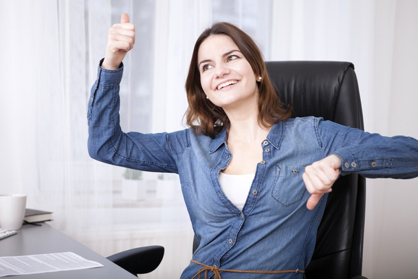 Undecided businesswoman doing a thumbs up and down - Photo, Image
