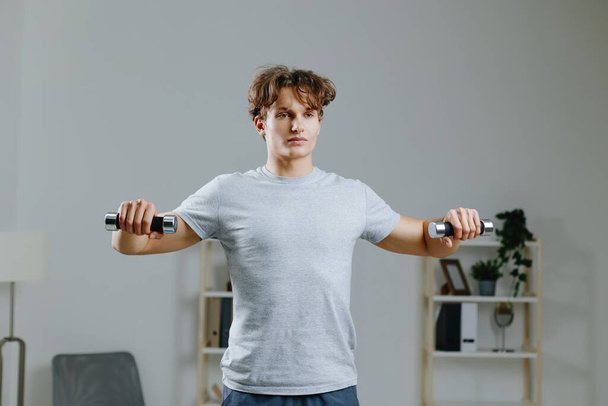 человек домашняя активность мат спортивная йога закрытый карантин тренировки здоровья комната отдыха абс осуществляя сильный человек взрослый здоровый гантели серый - Фото, изображение