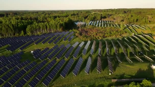 新しい太陽光発電所のトップビュー. 夏の日没の緑のフィールドの隣の現代太陽光発電パネルの流れ. 再生可能エネルギーの生産。 日没時のフィールドのソーラーパネル. - 映像、動画