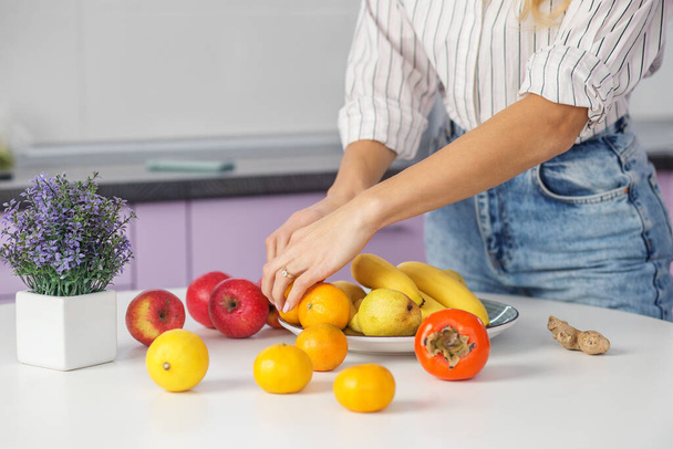 Comida ecológica. La mujer pone fruta en el plato en la cocina. Dieta y concepto de alimentación saludable. Antecedentes De cerca.. - Foto, imagen