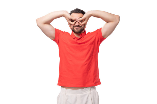 junge hübsche europäische brünette Mann mit Bart gekleidet in einem roten T-Shirt macht eine Fratze. - Foto, Bild