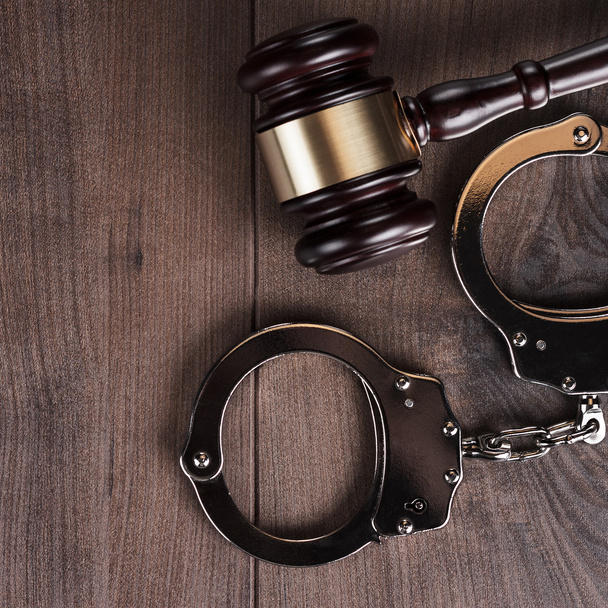 handcuffs and judge gavel on wooden background - Fotoğraf, Görsel