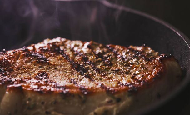 Καρυκευμένη μπριζόλα Tomahawk μαγειρεύεται σε ένα τηγάνι. - Φωτογραφία, εικόνα