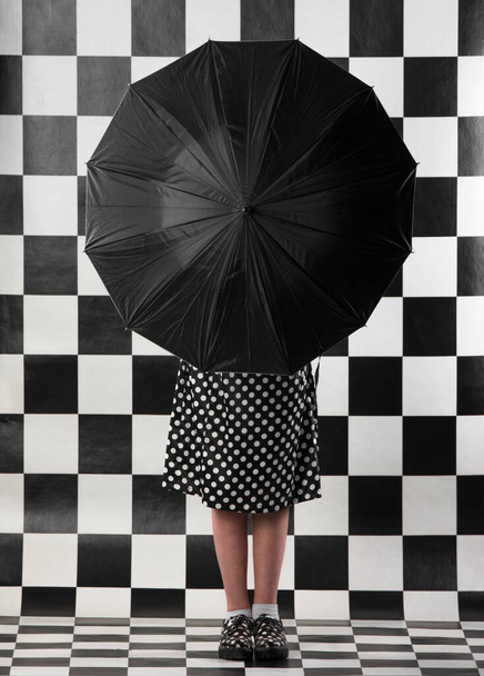 young woman in polka-dot dress and with a black umbrella - Photo, Image