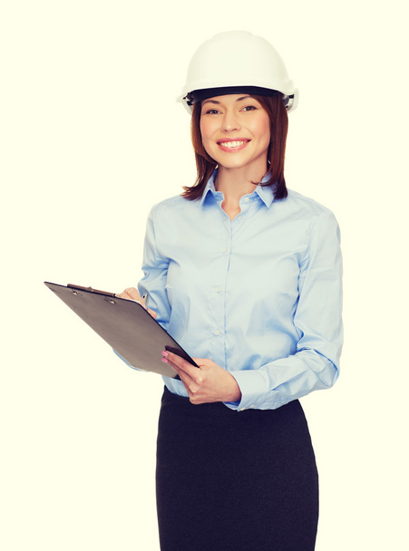 smiling businesswoman in helmet with clipboard - Foto, Bild