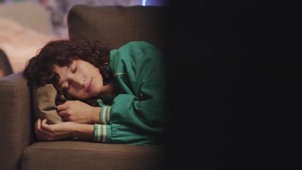 Panorámica de la joven Biracial con el pelo rizado que se duerme en el sofá mientras ve la televisión en la habitación iluminada por neón - Metraje, vídeo