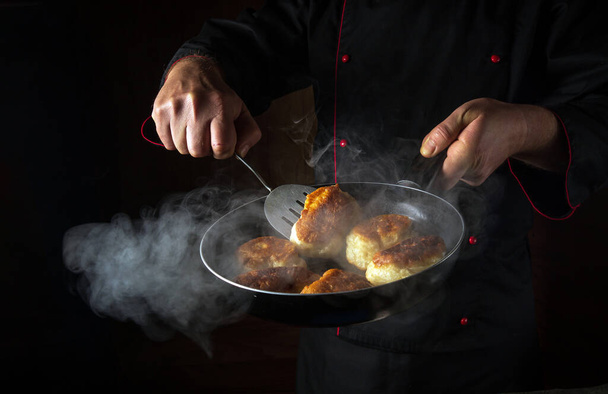 Lo chef sta preparando l'oladki in una padella. Il concetto di preparare piatto nazionale ucraino o bliny in cucina. Spazio nero per ricetta o menu. - Foto, immagini