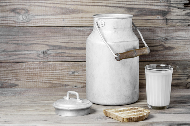 Some bread, a milk glass and a  milk can  on a wooden background - 写真・画像