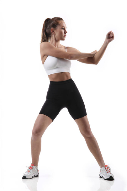 Mulher apta atraente exercitando-se em estúdio com copyspace. Imagem de uma jovem atleta saudável fazendo exercícios de fitness contra fundo branco. - Foto, Imagem