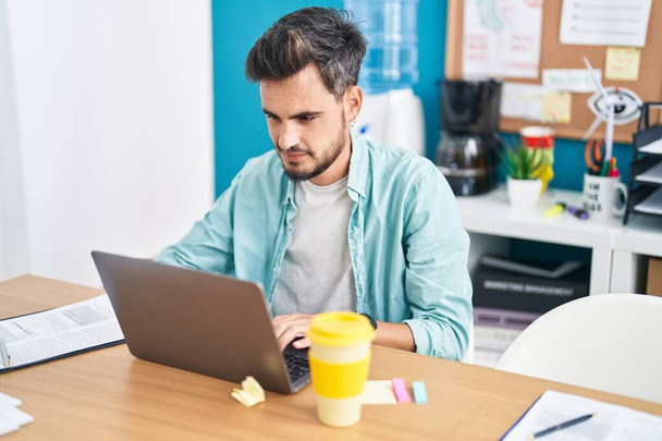 Young hispanic man business worker using laptop working at office - Foto, imagen